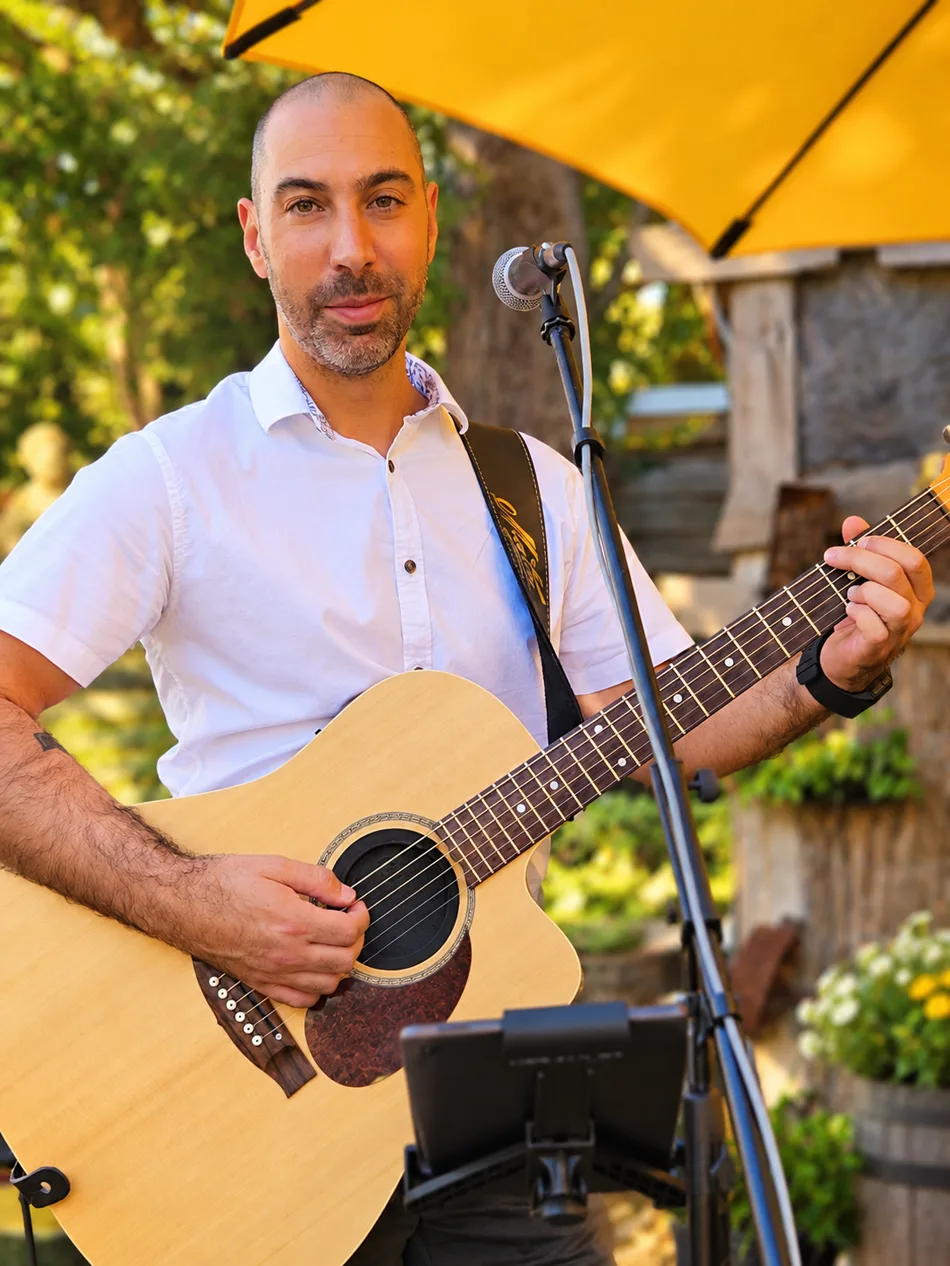 Dan with his acoustic guitar, looking towards the camera